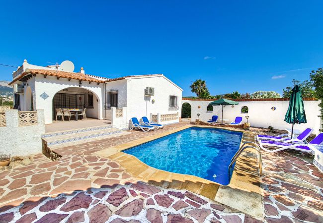 Zona de terraza de piscina con tumbonas y sombrillas en villa de Calpe