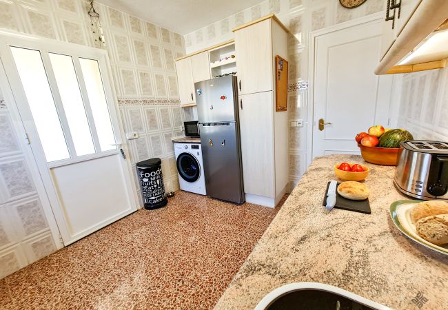 Kitchen with exit to outside porch, washing machine and fridge of villa for rent Calpe near Calalga Beach